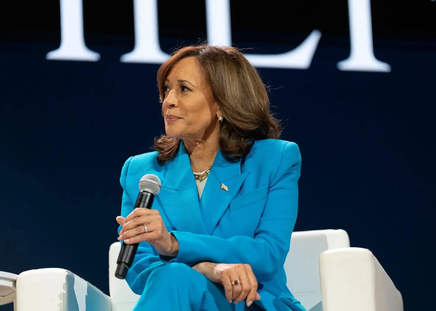 Harris speaking on a mic seated