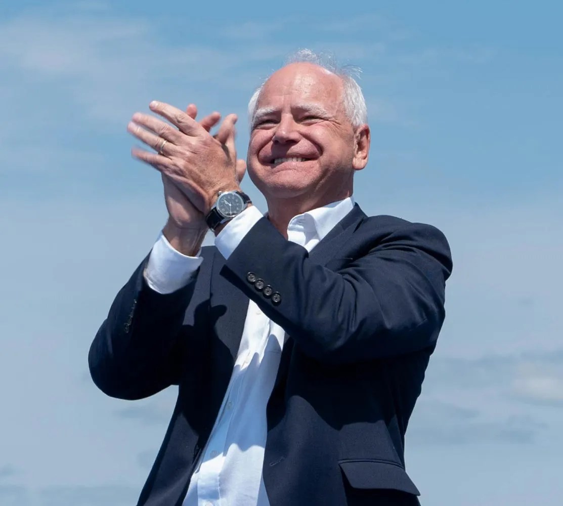 Governor Walz clapping with the sky behind him