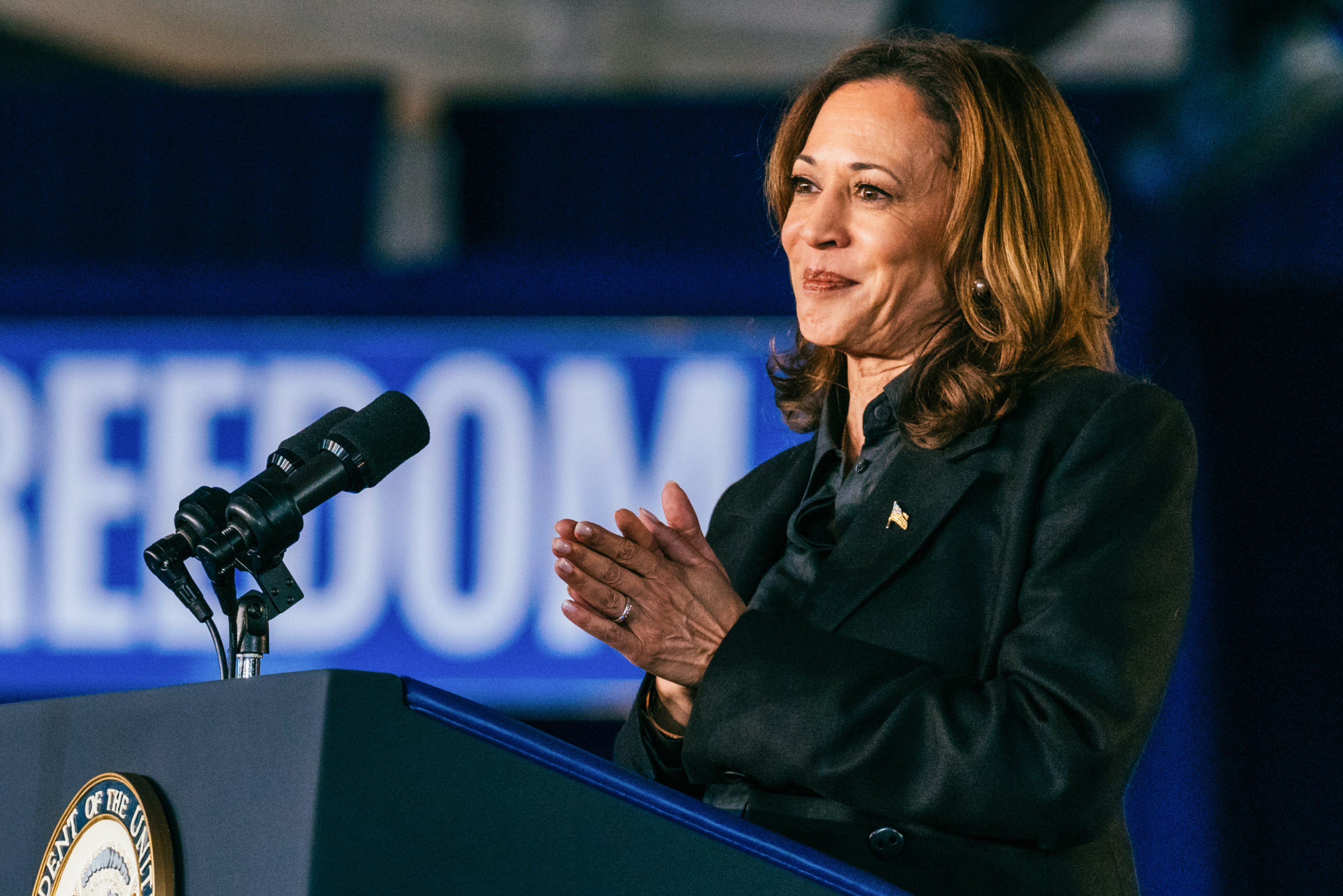 Kamala Harris standing at a podium clapping